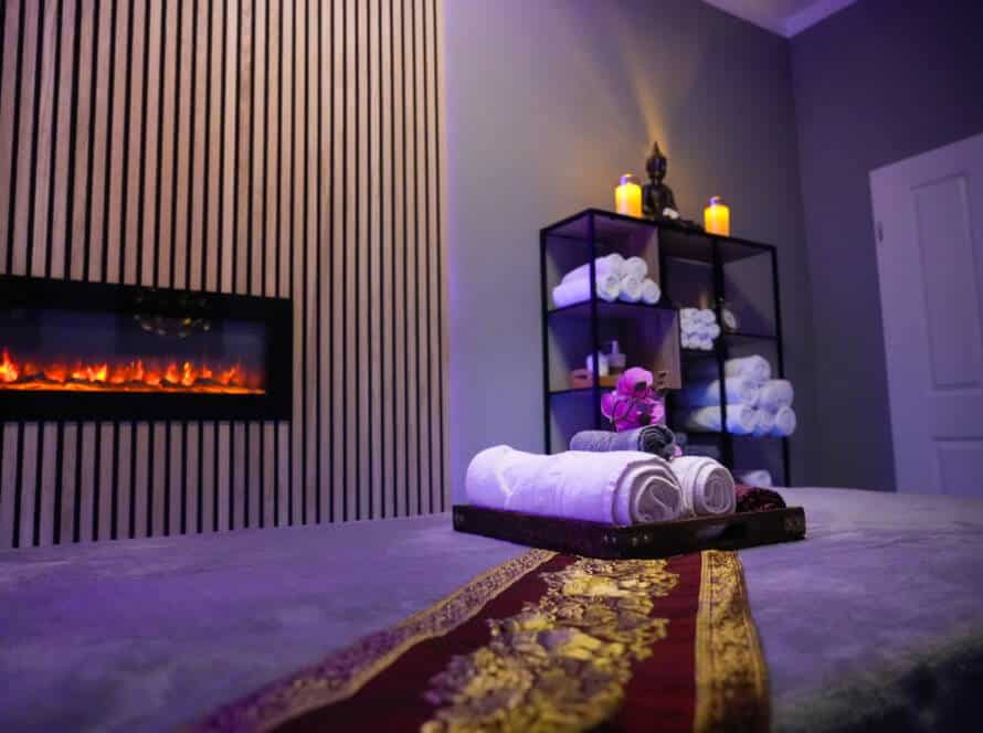 Behandlungsraum für Thai Massage in Nürnberg mit Massageliege, Kamin und Handtüchern